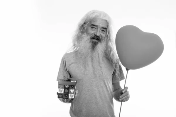 Estudio de tiro de hombre barbudo alto feliz sonriendo mientras sostiene el globo en forma de corazón y caja de regalo listo para el día de San Valentín — Foto de Stock