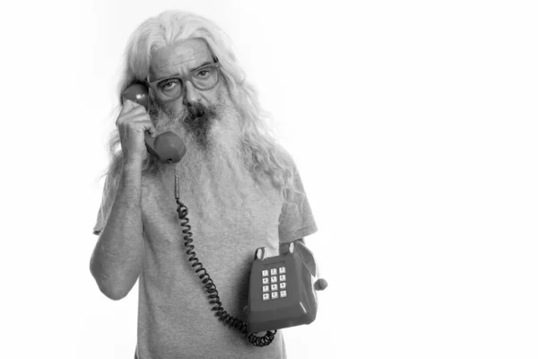 Studio shot van senior bebaarde man praten op oude telefoon — Stockfoto