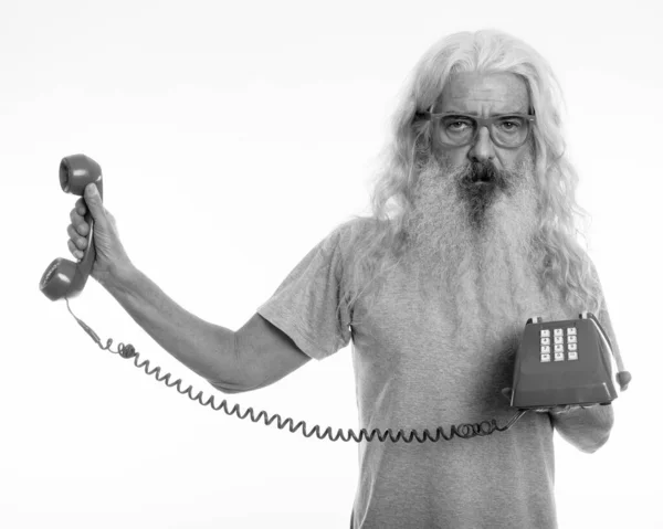 Studio shot van senior bebaarde man met oude telefoon, terwijl op zoek geïrriteerd — Stockfoto
