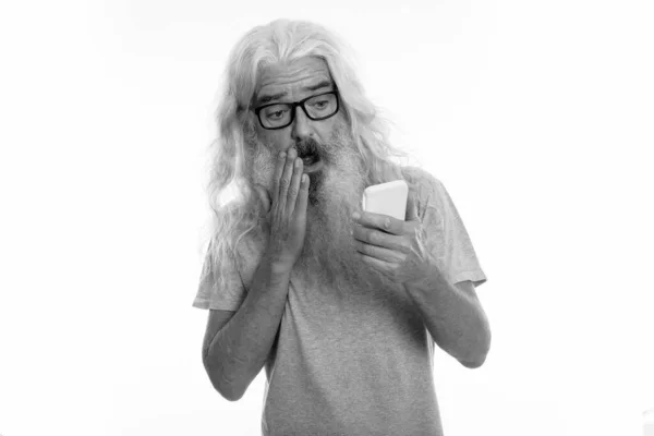 Studio colpo di anziano barbuto uomo utilizzando il telefono cellulare, mentre guardando scioccato e la bocca di copertura — Foto Stock