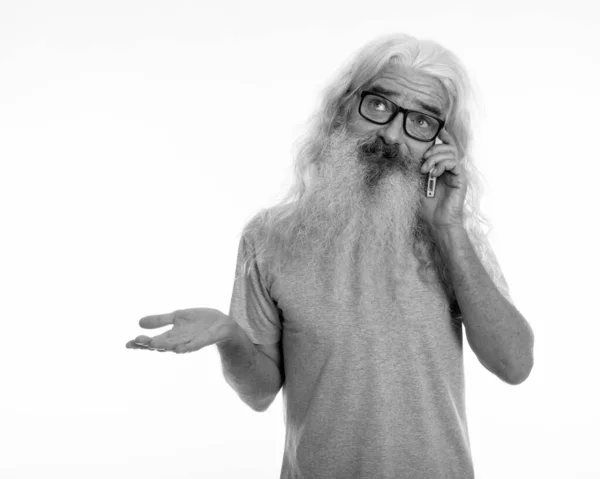 Stúdió felvétel idős szakállas férfi gondolkodás közben nézett zavaros és beszél a mobiltelefon — Stock Fotó