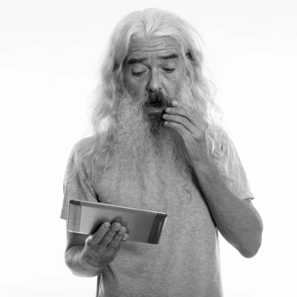 Studio colpo di anziano uomo barbuto cercando scioccato durante l'utilizzo di tablet digitale e toccare i baffi — Foto Stock