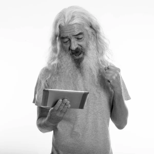 Studio colpo di felice anziano barbuto uomo sorridente e cercando motivato durante l'utilizzo di tablet digitale — Foto Stock
