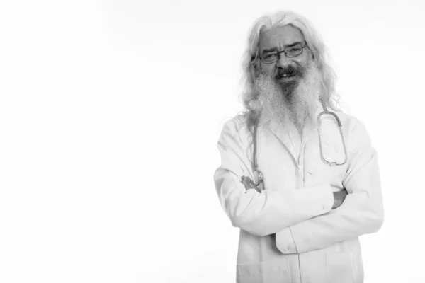 Studio colpo di felice anziano barbuto uomo medico sorridente mentre indossa occhiali con le braccia incrociate — Foto Stock