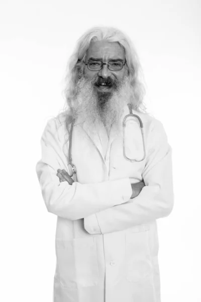 Studio colpo di felice anziano barbuto uomo medico sorridente mentre indossa occhiali con le braccia incrociate — Foto Stock