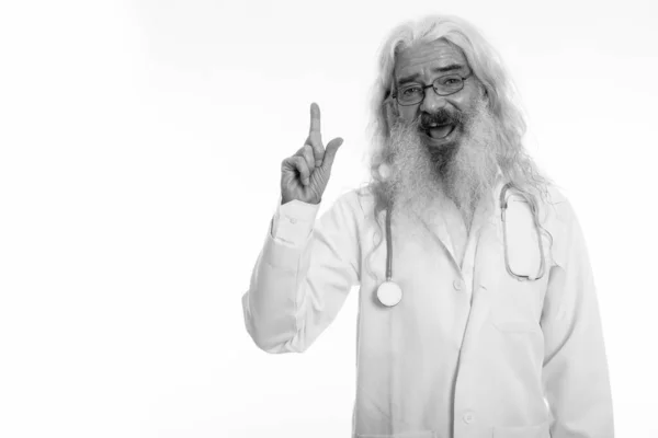 Studio colpo di felice anziano barbuto uomo medico sorridente mentre punta il dito verso l'alto — Foto Stock