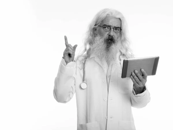 Studio colpo di anziano barbuto medico pensare mentre punta il dito verso l'alto e tenendo tablet digitale — Foto Stock