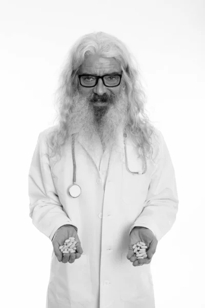 Studio shot di felice anziano barbuto uomo medico sorridente mentre indossa occhiali e tenendo compresse di vitamina — Foto Stock