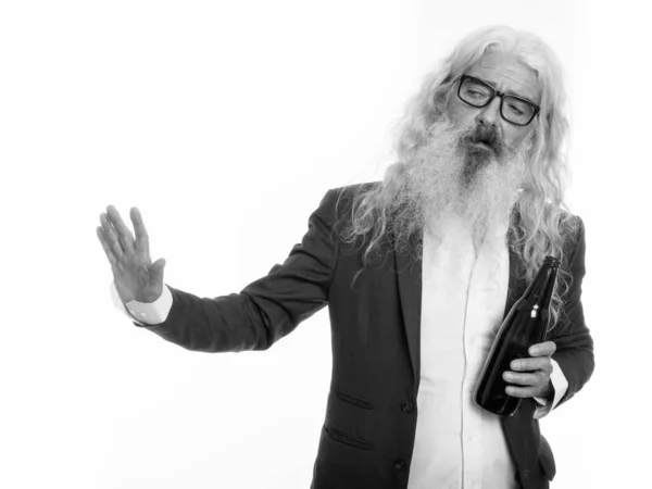 Студийный снимок старшего бородатого бизнесмена, держащего бутылку пива и показывающего стоп-сигнал сбоку — стоковое фото