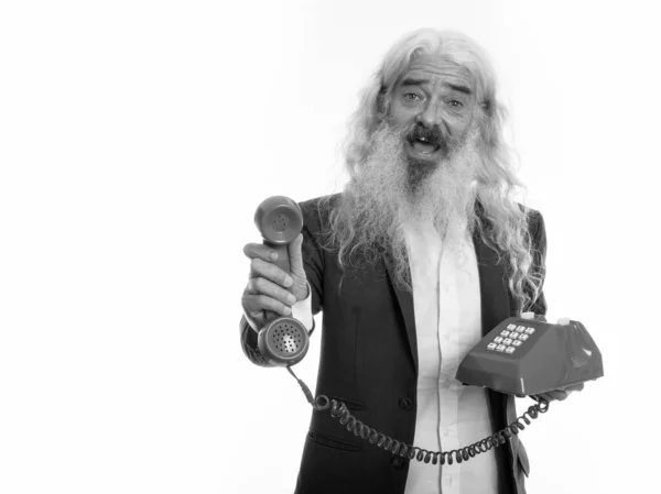 Studio shot of happy senior bearded businessman smiling while giving old telephone — Stock Photo, Image