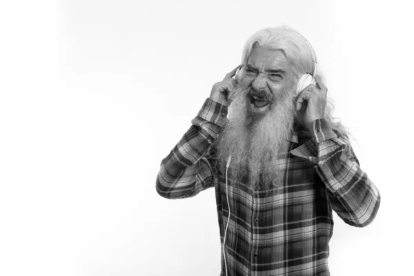 Студійний знімок щасливого старшого бородатого чоловіка, який посміхається і співає, слухаючи музику — стокове фото