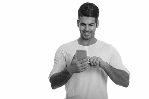 Joven feliz hombre persa sonriendo mientras usa el teléfono móvil —  Fotos de Stock