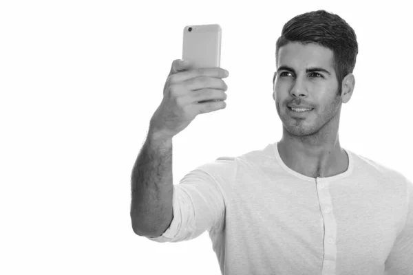 Joven hombre persa feliz sonriendo y tomando selfie con teléfono móvil —  Fotos de Stock