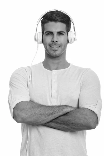 Young happy Persian man smiling and listening to music with arms crossed — Stock Photo, Image