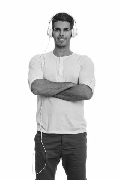 Young happy Persian man smiling and listening to music with arms crossed — Stock Photo, Image
