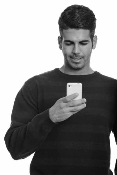 Młody szczęśliwy Perski mężczyzna uśmiecha się i używa telefonu komórkowego — Zdjęcie stockowe
