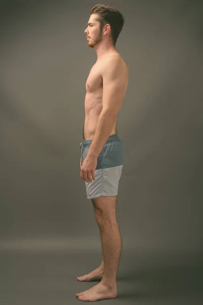 Jonge knappe bebaarde man shirtloos tegen grijze achtergrond — Stockfoto