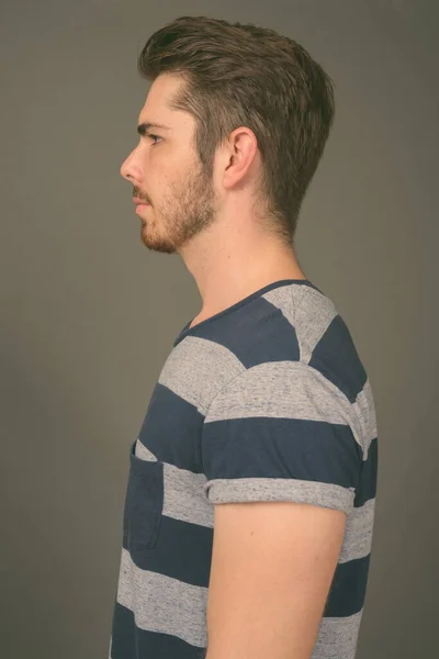 Young handsome bearded man against gray background — Stock Photo, Image