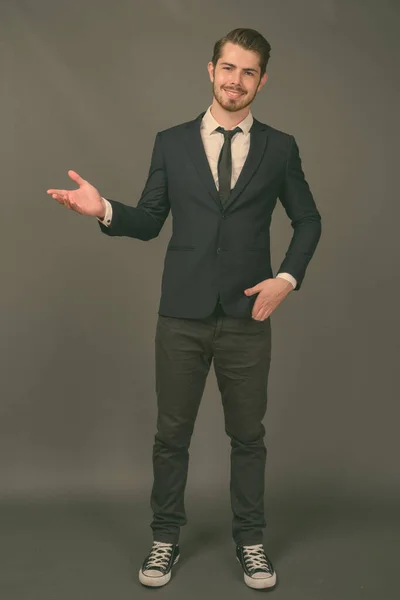 Young handsome bearded businessman against gray background — Stock Photo, Image