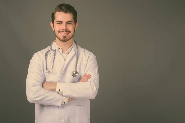 Молодий красивий бородатий чоловік лікар на сірому фоні — стокове фото