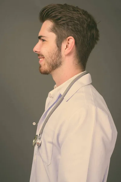 Jeune beau barbu homme médecin sur fond gris — Photo