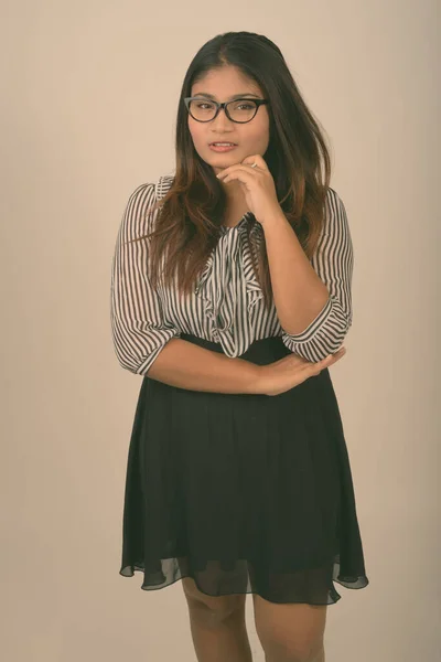 Studio skott av ung fet persisk affärskvinna stående och tänkande samtidigt bär glasögon mot grå bakgrund — Stockfoto