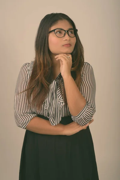 Studio colpo di giovane donna d'affari persiana grasso pensando mentre guardando verso l'alto e indossando occhiali su sfondo grigio — Foto Stock