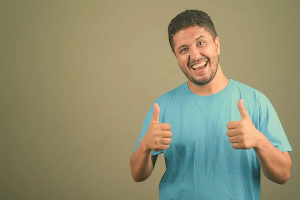 Baard Perzische man met blauw shirt tegen gekleurde achtergrond — Stockfoto