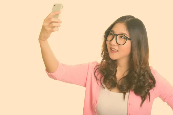 Young happy Asian woman taking selfie with mobile phone — Stock Photo, Image