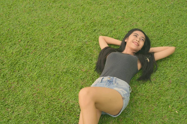 Jovem bela mulher asiática relaxante no parque — Fotografia de Stock