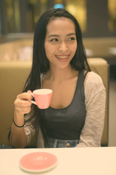 Joven hermosa mujer asiática relajándose dentro de la cafetería — Foto de Stock