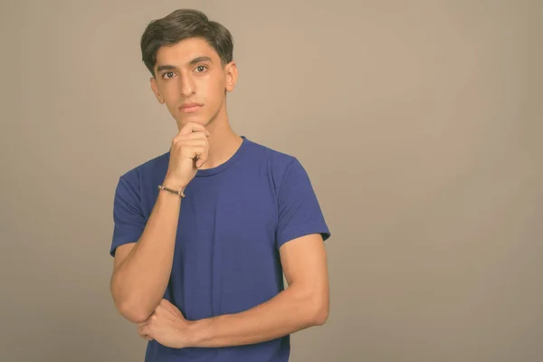 Joven guapo adolescente persa contra fondo gris — Foto de Stock