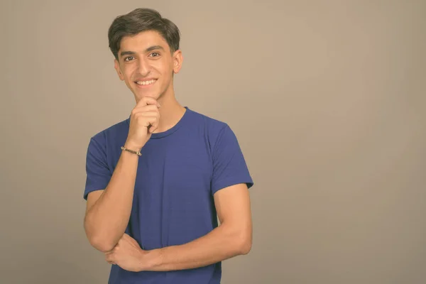 Jong knap Perzisch tiener jongen tegen grijs achtergrond — Stockfoto