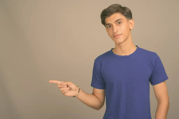 Young handsome Persian teenage boy against gray background — Stock Photo, Image