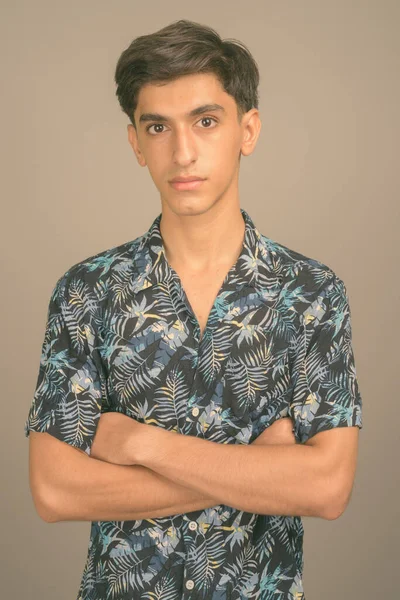 Junger gutaussehender persischer Teenager trägt Hawaiihemd vor grauem Hintergrund — Stockfoto