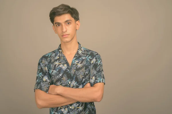 Mladý pohledný perský dospívající chlapec na sobě havajské tričko proti šedému pozadí — Stock fotografie