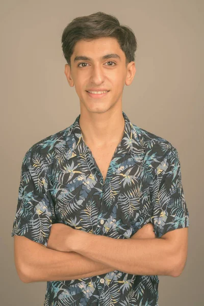 Jong knap Perzisch tiener jongen dragen Hawaiian shirt tegen grijs achtergrond — Stockfoto