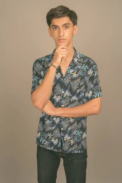 Young handsome Persian teenage boy wearing Hawaiian shirt against gray background — Stock Photo, Image