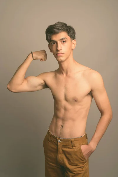 Young handsome Persian teenage boy shirtless against gray background — Stock Photo, Image
