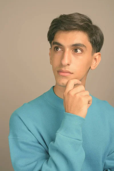 Gri arka planda genç yakışıklı İranlı genç çocuk — Stok fotoğraf