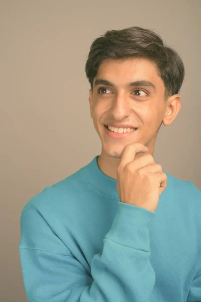 Young handsome Persian teenage boy against gray background — Stock Photo, Image