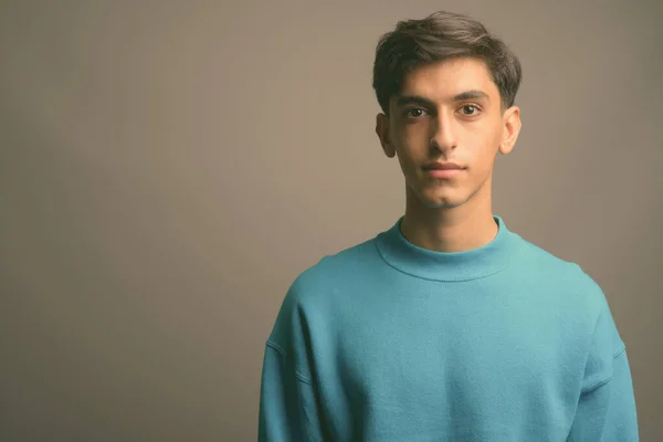 Junger gutaussehender persischer Teenager vor grauem Hintergrund — Stockfoto