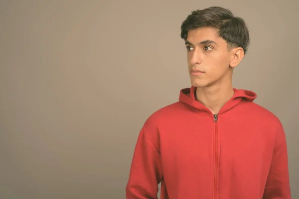 Junger gutaussehender persischer Teenager vor grauem Hintergrund — Stockfoto