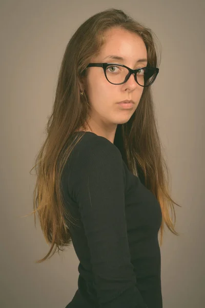 Portrait of young beautiful woman against gray background — Stock Photo, Image