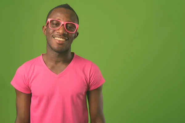 スタジオショットの若いですアフリカ人男性のピンクのシャツを着て緑の背景 — ストック写真