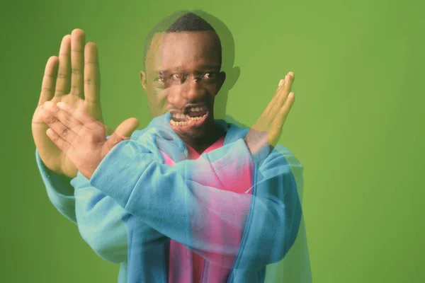 工作室拍摄的年轻非洲男子身穿蓝色夹克 绿色背景的粉色衬衫 — 图库照片
