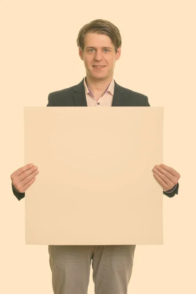 Πορτρέτο του νεαρού όμορφου επιχειρηματία με κοστούμι που δείχνει λευκό πίνακα — Φωτογραφία Αρχείου