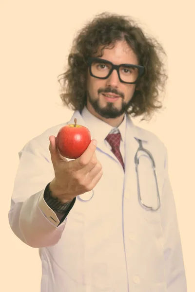 Студийный снимок красивого мужчины-врача, дающего красное яблоко с акцентом на яблоко — стоковое фото