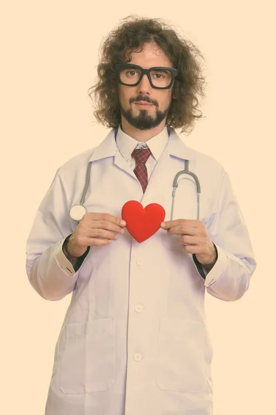 Студийный снимок красивого врача, держащего красное сердце обеими руками — стоковое фото
