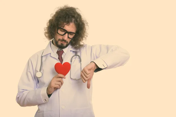 Грустный человек доктор держит красное сердце, давая большой палец вниз — стоковое фото